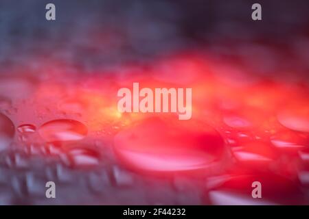 Wet dark glowing abstract background. Blue, purple, and fire colors. Macro Stock Photo