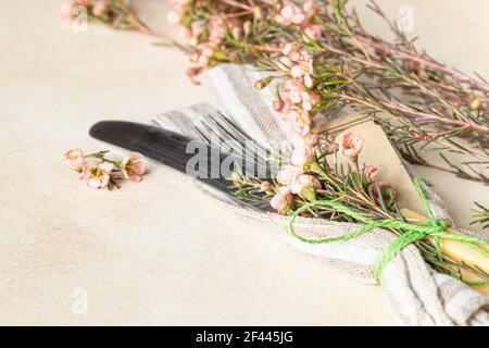 Cutlery set and beautiful pink flowers on light stone table. Easter celebration. Selective focus. Stock Photo