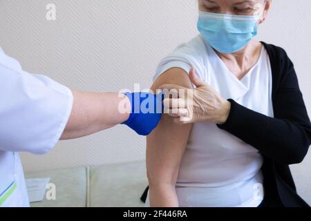 Woman being vaccinated in her hands on a white background in a hospital. Routine vaccination against flu and colds, coronavirus. Stock Photo