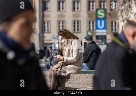 munich, germany - march 06 2020: young woman with face mask on her phone. Stock Photo