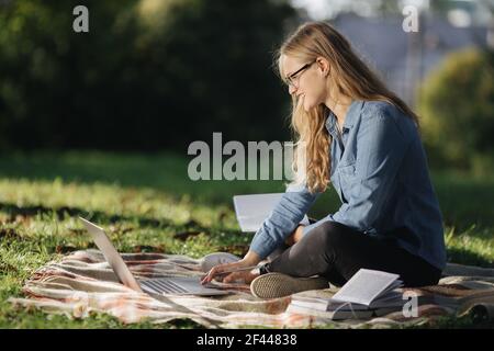 Smiling woman using laptop and taking notes outdoors Stock Photo