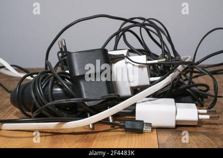 Pile of used smartphone wired chargers,electronic waste,tech device tools  Stock Photo