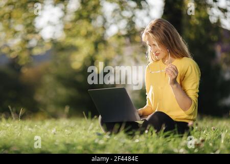 Pleasant woman relaxing outdoors and using laptop Stock Photo
