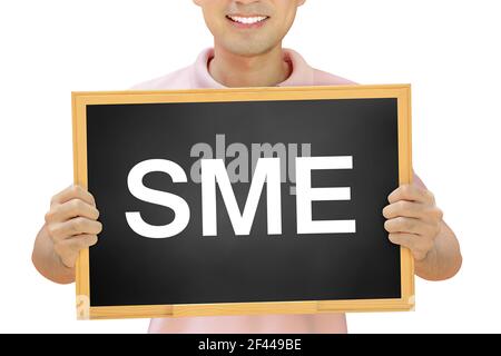SME (or Small and Medium Enterprise ) sign on blackboard held by smiling man Stock Photo