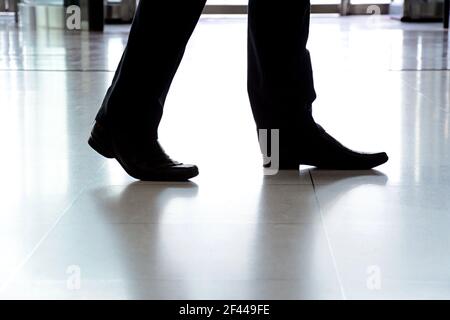 Businessman legs with black leather shoes walking on the floor Stock Photo