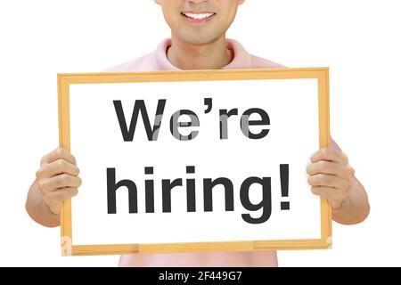 We're hiring sign on white board held by smiling man Stock Photo