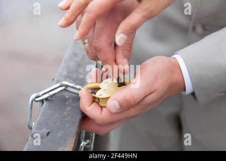 the bride and groom's hands close the heart-shaped lock. signs at the wedding. High quality photo Stock Photo