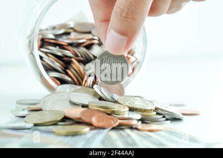 Hand picking up 100 Japanese yen (JPY) coin out of multi-currency pile of coins Stock Photo