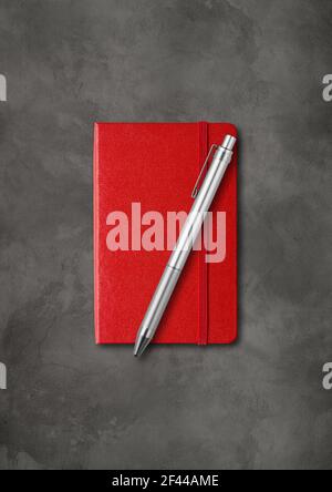 Red closed notebook with a pen. Mockup isolated on dark concrete background Stock Photo