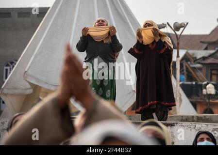 Kashmiri Muslim devotees raise hands while beseeching for blessings as the head priest (not framed) displays relic believed to be from beard of Prophet Muhammad during the celebration.Devotees from across Kashmir thronged the revered Hazratbal shrine for congregational prayers and to have a glimpse of the holy relic of Islamic Prophet Muhammad on the occasion following of Meraj-ul-Alam (ascension to heaven) in Srinagar. Stock Photo