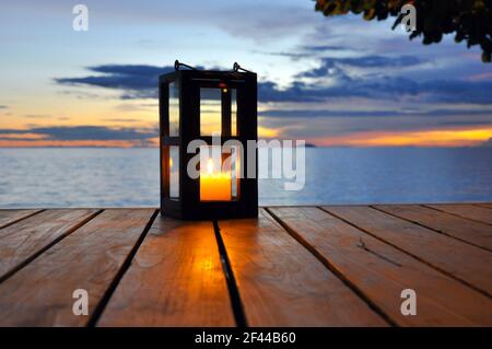 Candle lantern on wooden table with twilight sea background Stock Photo