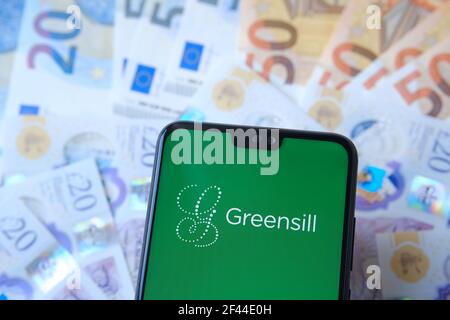 Greensill logo seen on the smartphone and blurred cash on the background. Greensill Capital was a financial services company which filed for insolvenc Stock Photo