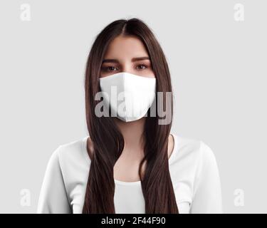 A mockup of a white cloth mask to protect against coronavirus, covid19, from an epidemic, for mass self-isolation. Respirator on a dark-haired girl, i Stock Photo