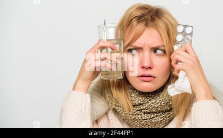Ways to feel better fast. Flu home remedies. Woman wear warm scarf because illness or flu. Girl hold glass water tablets and thermometer light Stock Photo