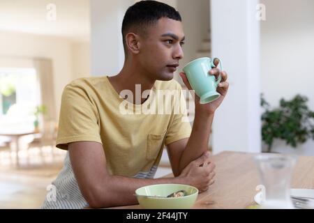 Mixed race man sitting at table and eating breakfast Stock Photo