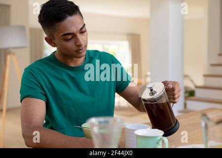 Mixed race man sitting at table and eating breakfast Stock Photo