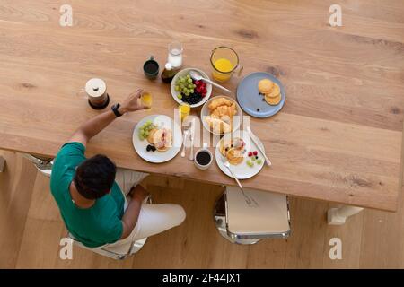 Mixed race man sitting at table and eating breakfast Stock Photo