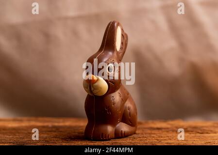 cute chocolate easter bunny on warm background with soft natural light on wooden table Stock Photo