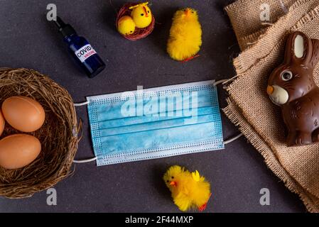 easter and covid19 concept. flat lay with face mask and covid vaccine with easter symbols like easter eggs and chocolate bunny Stock Photo