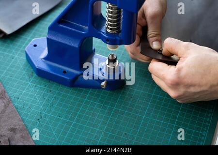 Artisan using hand press for setting snaps in leather for makes a wallet. Hand Pressure Snap Pressing Machine is using by craftsman in leather Stock Photo