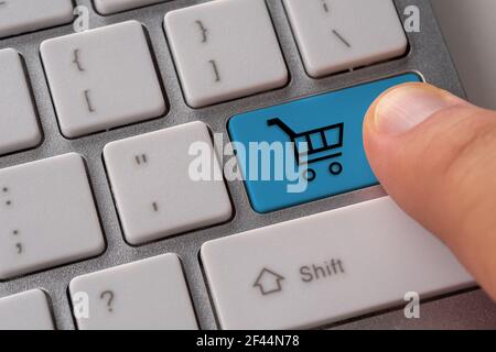 Male hand pressing keyboard button with shopping cart. Shopping online concept. Stock Photo