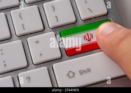 Male hand pressing keyboard button with flag of Iran on it. Online international business concept. Stock Photo
