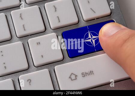 HERAKLION, Greece - July 20, 2020: Male hand pressing keyboard button with flag of NATO on it. Stock Photo