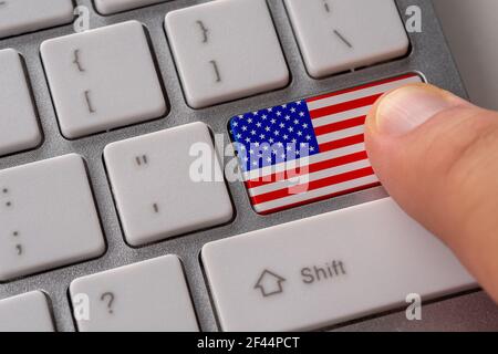 Male hand pressing keyboard button with flag of USA on it. Online international business concept. Stock Photo
