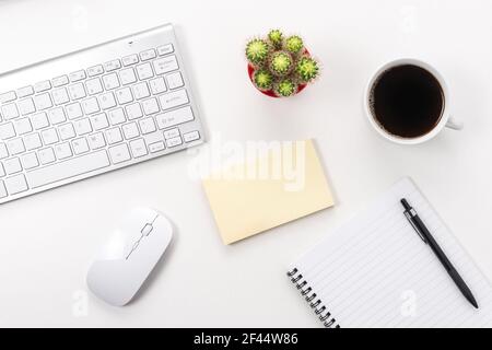White office desk table with blank notebook, computer keyboard and other office supplies. Top view with copy space. Stock Photo
