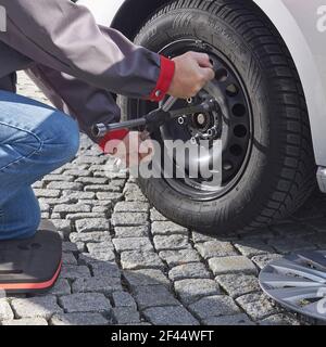 Man changing wheel on car outside,  using wheel wrench Stock Photo