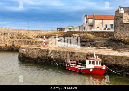 PORTSOY OLD HARBOUR MORAY FIRTH ABERDEENSHIRE SCOTLAND NEW OR RENOVATED HOUSES AND A RED BOAT Stock Photo