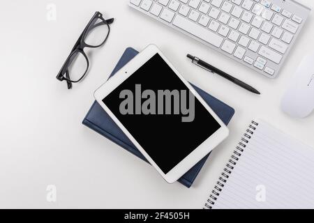 Workspace with computer keyboard, office supplies, and tablet on white background. Top view with copy space. Stock Photo