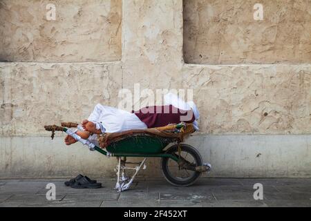 Qatar, Doha, Souk Waqif, Man asleep in wheel barrow Stock Photo