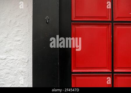 The red and black colored door and a white wall Stock Photo