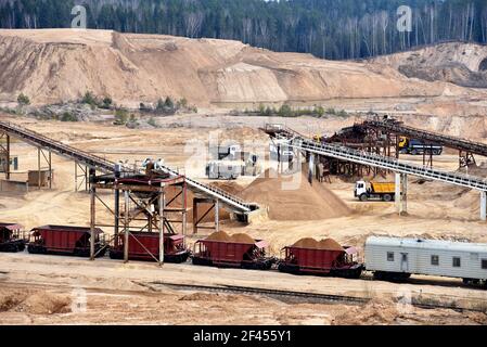 Loading sand into freight cars of a train in quarry. Sand Making Plant in open-pit mining. Crushing factory, machines and equipment for crushing, grin Stock Photo