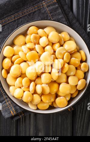 Pickled lupine beans close-up in a bowl on the table. Vertical top view from above Stock Photo