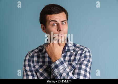 Pensive casual young man thinking isolated over blue background Stock Photo