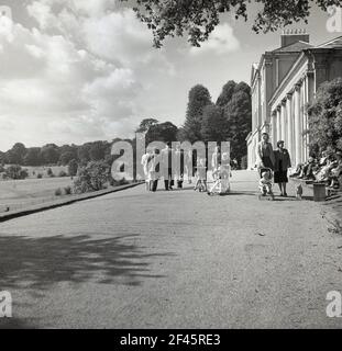 1950s, historical, familes outside Kenwood House at Hampstead Heath, North London, England, UK. A stately home, originally built in the 17th century, was remodelled by Robert Adam between 1764 and 1779 and was the home of Earls of Mansfield. In 1925 the house and some of the parkland was purchased by Edward Guinness, 1st Earl of Iveagh, who donated the estate to the nation. London County Council took ownership  and by the end of the 1920s, it was opened to the general public. Stock Photo
