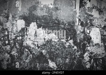 Old, rusty metal wall with remains of old posters and advertisements. Torn paper texture background. Black and white tone - retro monochrome BW color Stock Photo