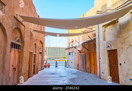 The narrow street leads to Dubai Creek and opens the view on old adobe houses of Al Fahidi and modern buildings of Deira, seen on the opposite bank of Stock Photo