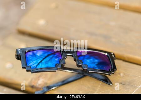 Black pixel sunglasses with blue lenses closeup in a sunny day. Selective focus Stock Photo