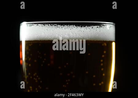 Close-up of a glass of beer with bubbles and foam on a dark background, macro Stock Photo