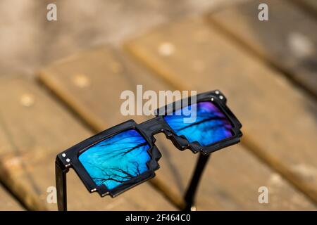 Black pixel sunglasses with blue lenses closeup in a sunny day. Selective focus Stock Photo