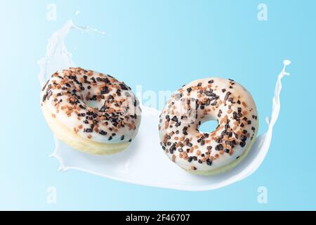 Fresh donuts with milk splashes on blue background. Minimal food concept. Stock Photo
