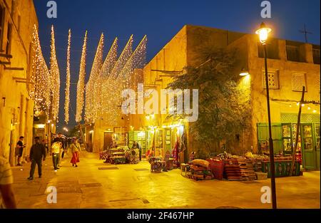 DUBAI, UAE - MARCH 8, 2020: The evening walk along the scenic streets of Al Fahidi with a view on carpet store, bright lanterns and old adobe houses, Stock Photo