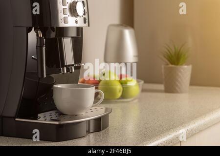 Modern espresso coffee machine with a cup in interior of kitchen closeup. Stock Photo
