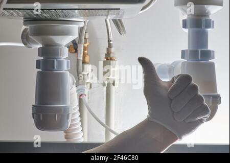 Plumber thumb up on pipes background close up view Stock Photo