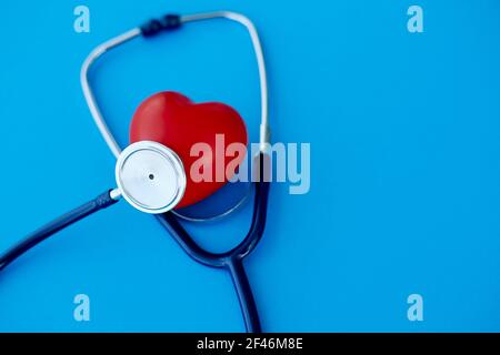 red heart and phonendoscope, isolated on a blue background. Stock Photo