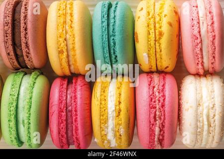 Closeup of delicious multicolored macaroons as a background. Mockup of greeting card with sweet multicolored macaron cakes. French almond meringue. Stock Photo