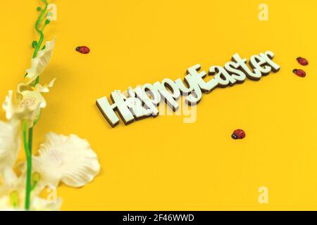 Happy Easter congratulatory festive background with text on yellow paper and with spring flowers Stock Photo